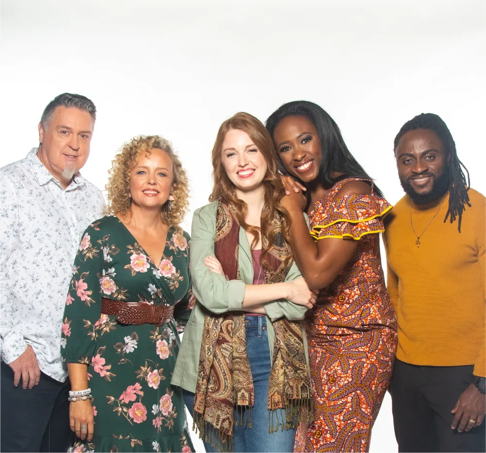 Three smiling women flanked by two men posing for a photo.